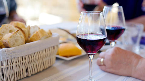 Frau sitzt mit einem Glas Rotwein am Tisch