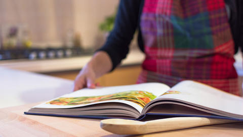 Frau mit Schürze blättert im Kochbuch der Herzstiftung
