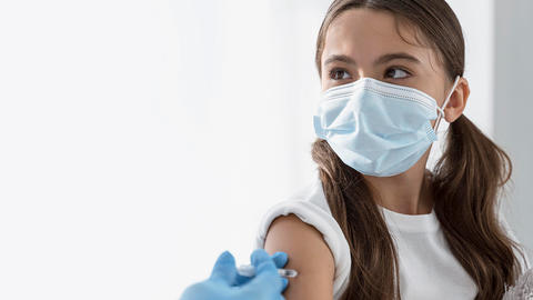 Kind bekommt mit Mundschutz eine Impfung
