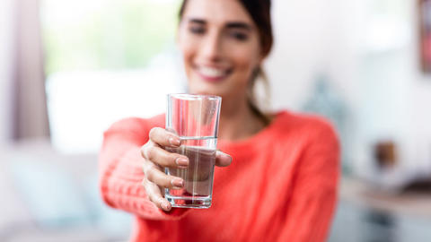 Frau hält ein Wasserglas in die Hand