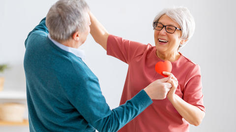 Senioren tanzen mit einem gebastelten Herz in der Hand