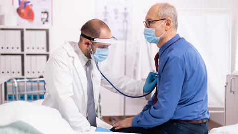 Arzt hört mit Stethoskop Herz ab